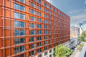 the facade of a tall orange building with many windows