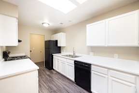 A kitchen with white cabinets and a black fridge.