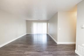 A room with wooden flooring and a window with blinds.