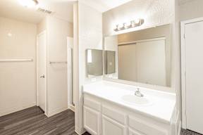 A white bathroom with a sink and mirror.