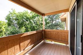 A wooden balcony with a door on the right side.