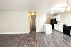 A kitchen area with a black refrigerator and white cabinets.