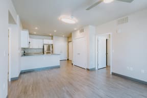 a living room and kitchen with a wood floor and white cabinets