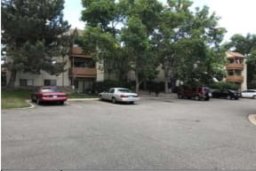 a parking lot with cars in front of an apartment building