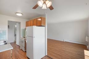 a kitchen with a white refrigerator and a wooden floor