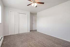a bedroom with white walls and a ceiling fan