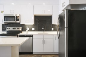 a kitchen with white cabinets and black and white appliances
