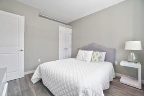 a bedroom with grey walls and a white bed with a white comforter