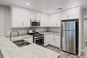 Modern kitchen with white cabinetry and stainless steel appliances at OSM Properties Homes & Apartments, California