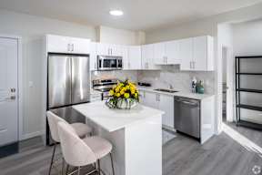 A modern kitchen with a white island and a refrigerator at Hills on 36, Edmonton Alberta