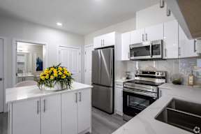 A modern kitchen with white cabinets and stainless steel appliances.at Hills on 36, Edmonton Alberta
