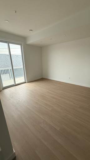 A room with wooden flooring and a sliding glass door.