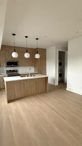 A modern kitchen with a wooden island and pendant lights.