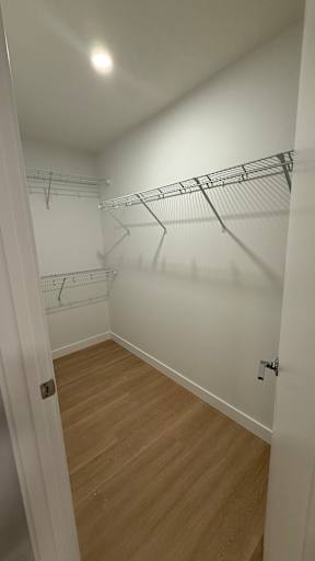A white hallway with a wooden floor and a white door.