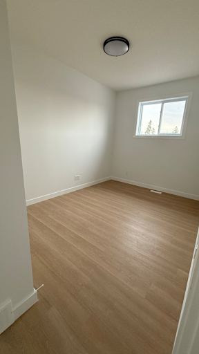 A room with a window and a wooden floor.