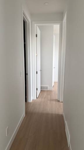 A long hallway with white walls and wood flooring.