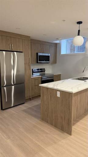 A modern kitchen with a stainless steel refrigerator and wooden cabinets.