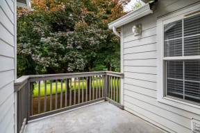 a balcony with a wooden railing and a gray house with white siding