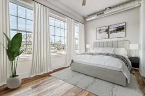 a bedroom with a bed and windows with white curtains