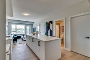 a kitchen with an island and a living room in the background