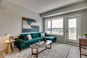 a living room with a green couch and a large window