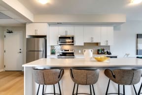a kitchen with white cabinets and a large island with three stools