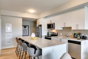 a kitchen with white cabinets and a large island with four chairs