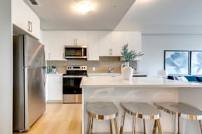 a kitchen with white cabinets and a white island with three stools