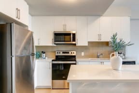 a kitchen with white cabinets and stainless steel appliances