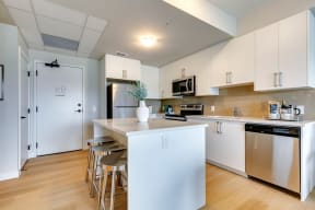 a kitchen with white cabinets and a white island with three stools