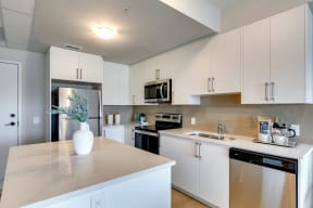 a kitchen with white cabinets and a white vase with a plant on the counter