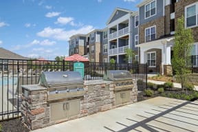 a patio with a grill and a house in the background