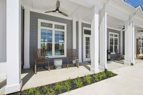the front porch of a home with two chairs and a table