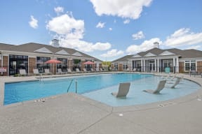 a swimming pool with chairs and a building in the background