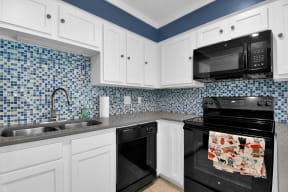a kitchen with white cabinets and black appliances