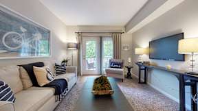 A living room with a white couch and a painting of a bicycle on the wall.