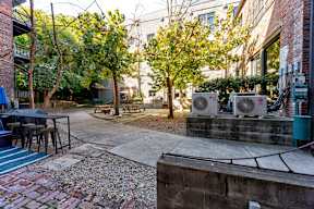 A courtyard with a brick wall and a tree with a metal structure on it.
