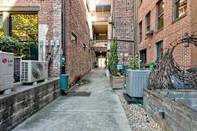 A narrow alley with brick buildings and air conditioning units on the side.