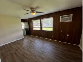 an empty room with a ceiling fan and three windows