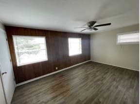 an empty room with a ceiling fan and three windows