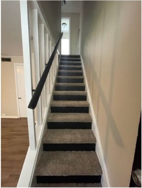 a staircase with a black railing and a gray carpet