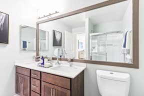 A bathroom with a white countertop and brown cabinets.