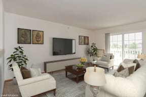 A living room with a white couch, a brown armchair, a wooden coffee table, and a flat-screen TV mounted on the wall.