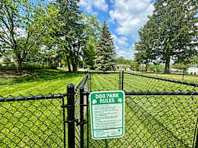 A sign on a fence that says Dog Park Rules.