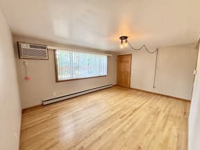 an empty living room with wood floors and a window
