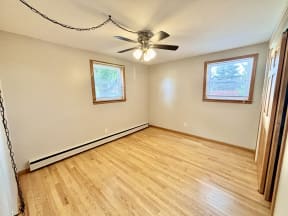 an empty living room with wood floors and a ceiling fan