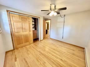 an empty living room with a wooden door and a ceiling fan