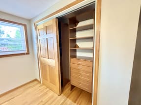 a closet in a small room with wooden floors and a window