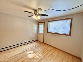 an empty living room with a ceiling fan and a window