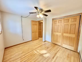 an empty living room with wood floors and a ceiling fan